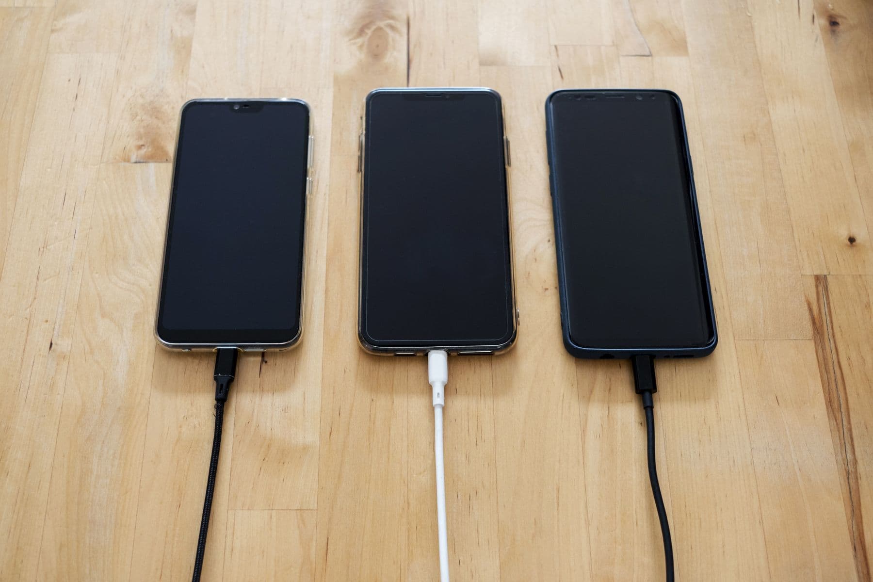 Three devices in a row on a wooden bench, each plugged into a cable